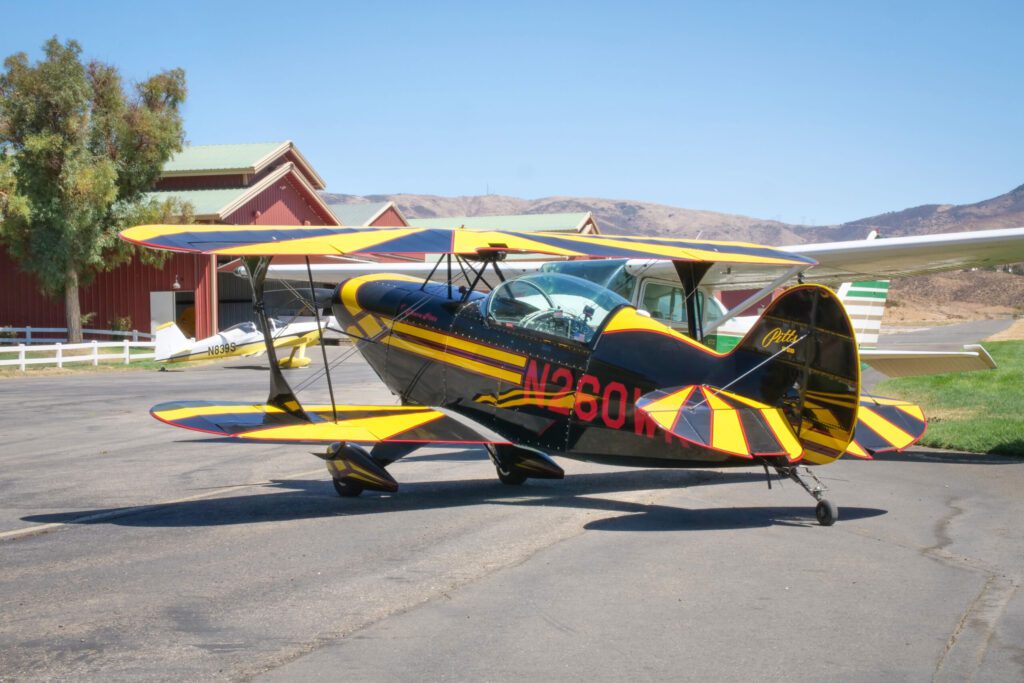The Pitts Bi-Plane sits idle at Van Nuys airport. Small aircraft in background.