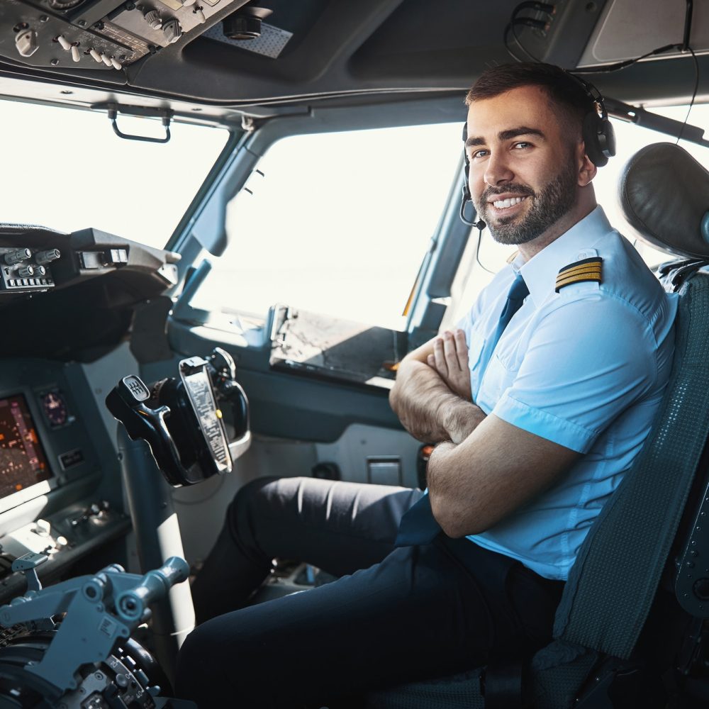 Flight Academy graduate sitting in co-pilot seat in uniform, smiling.